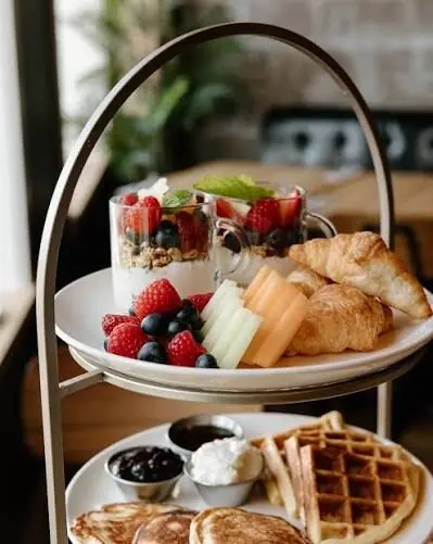 Berry yogurt parfaits, fresh fruit, croissants and waffles on a tiered stand