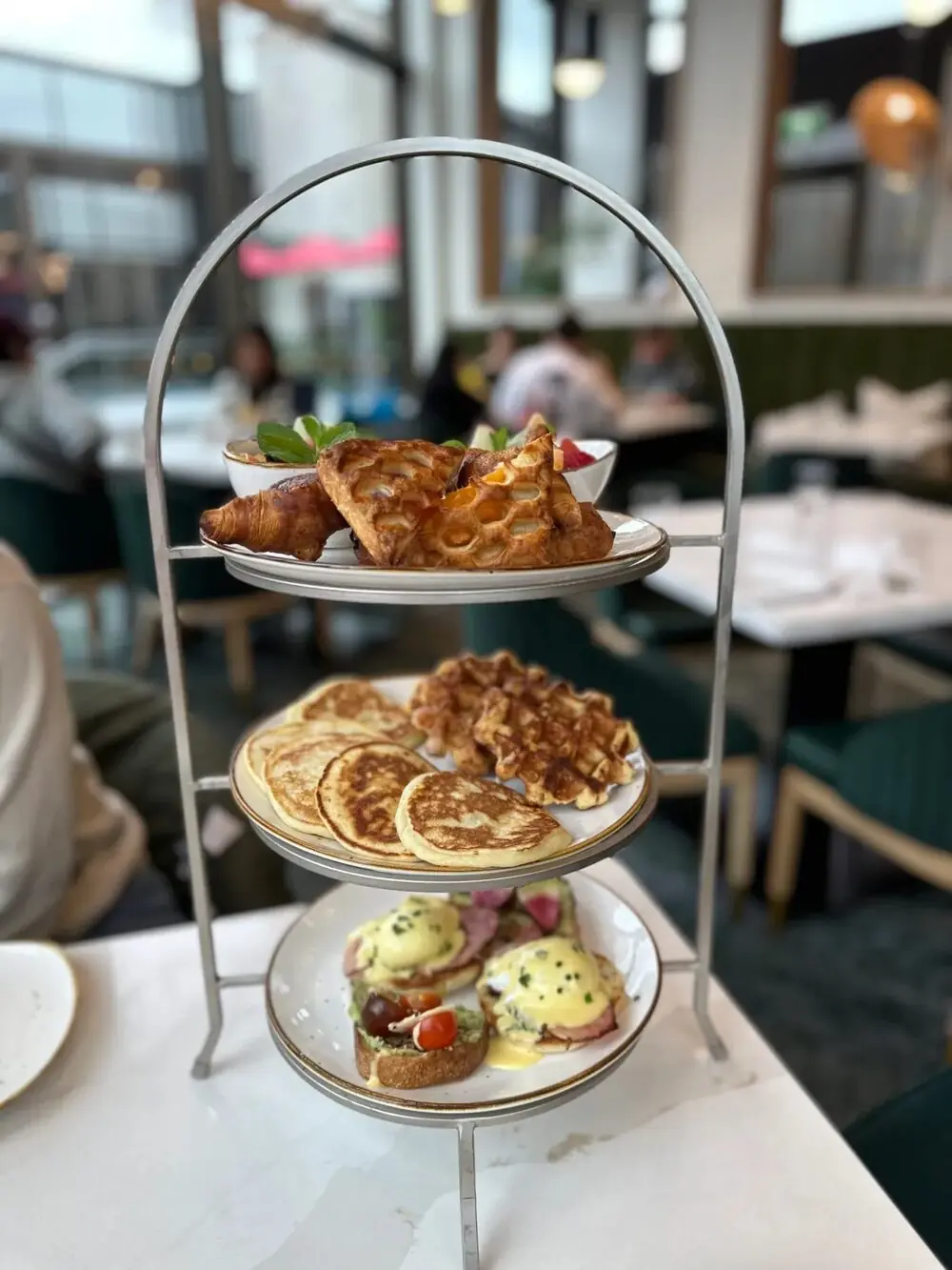 Three-tier breakfast stand at Bow & Stern with croissants and danishes, pancakes and waffles, and eggs Benedict with avocado toast